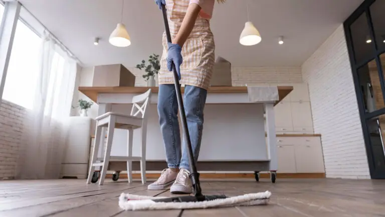 Professional cleaner from Nantucket cleaning services mopping hardwood floors in a modern kitchen with moving boxes in the background.