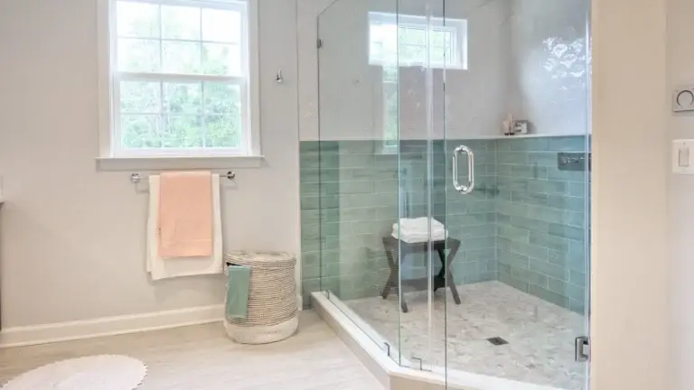 Bright clean bathroom with a glass shower enclosure and green tile walls.