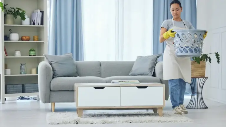Professional cleaner carrying laundry basket in living room