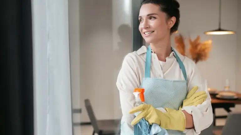 Smiling woman wearing apron and cleaning gloves