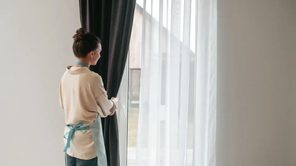 Woman opening curtains near bright window