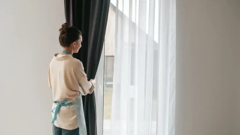 Woman opening curtains near bright window